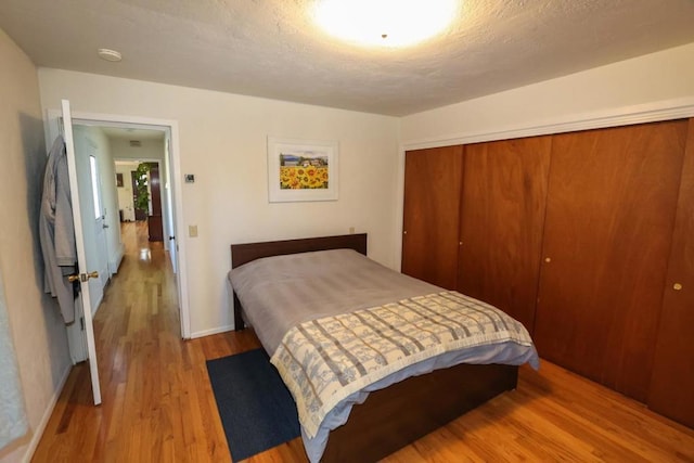 bedroom featuring a textured ceiling, light wood-type flooring, and a closet