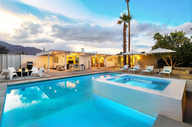 view of swimming pool with a mountain view, a patio area, and an in ground hot tub