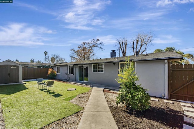 back of house with a lawn and a storage unit