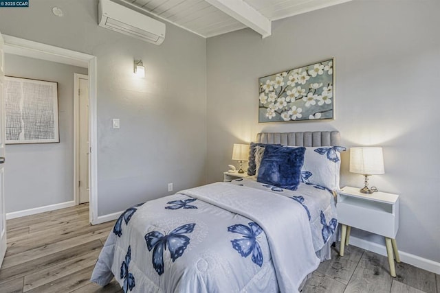 bedroom featuring a wall mounted air conditioner, beam ceiling, and light hardwood / wood-style flooring