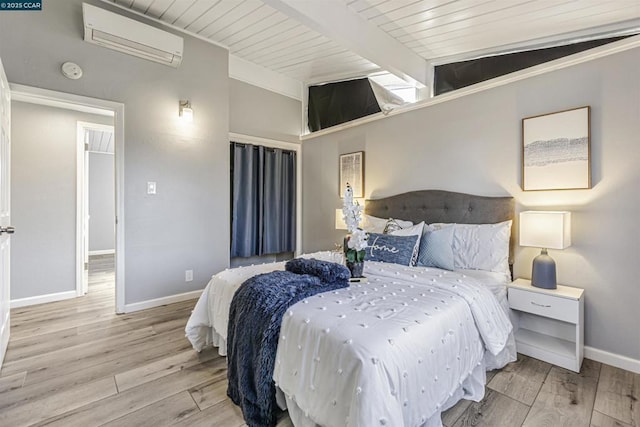 bedroom featuring vaulted ceiling with beams, light hardwood / wood-style floors, and an AC wall unit