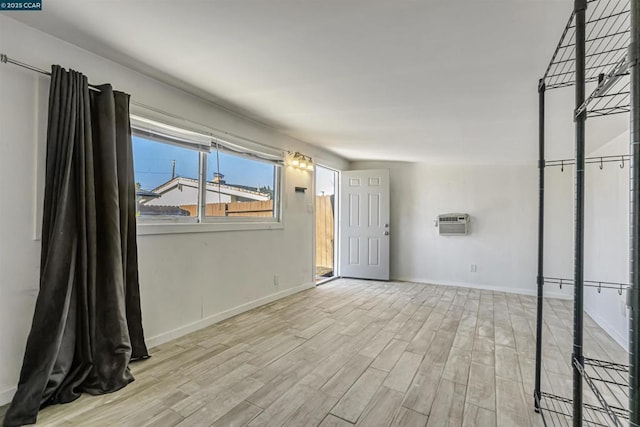 spare room with a wall unit AC and light wood-type flooring