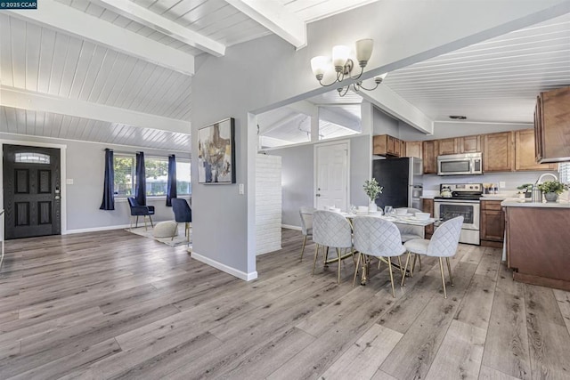 dining room with vaulted ceiling with beams, an inviting chandelier, and light wood-type flooring