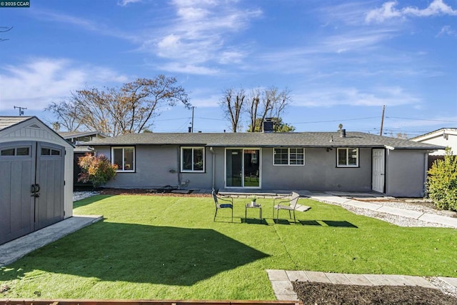 rear view of house featuring a yard and a storage shed