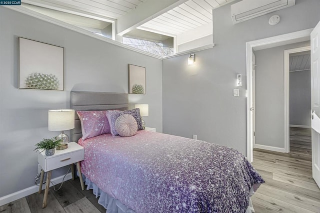 bedroom featuring lofted ceiling with beams, a wall mounted air conditioner, and light hardwood / wood-style floors