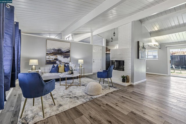 living room featuring hardwood / wood-style flooring, lofted ceiling with beams, and a brick fireplace