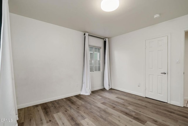 empty room with baseboards and wood finished floors