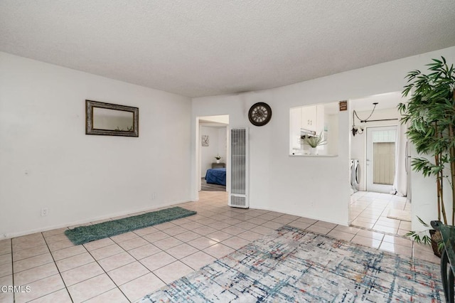 spare room with a textured ceiling, light tile patterned flooring, and baseboards