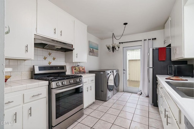 kitchen featuring tasteful backsplash, stainless steel gas range, under cabinet range hood, black microwave, and separate washer and dryer