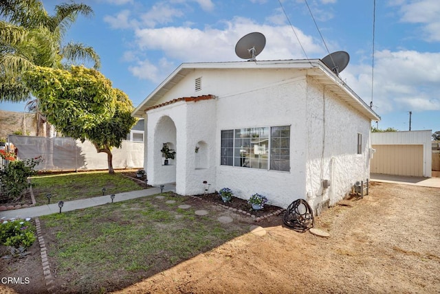 mediterranean / spanish-style house featuring fence, an outdoor structure, and stucco siding