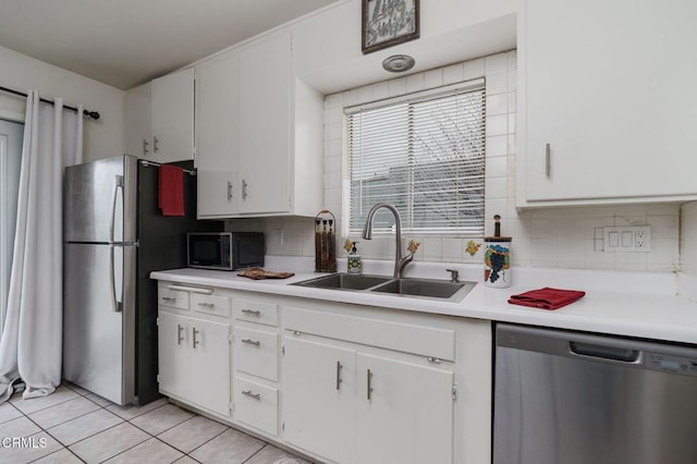 kitchen featuring a sink, stainless steel appliances, white cabinetry, backsplash, and light tile patterned flooring