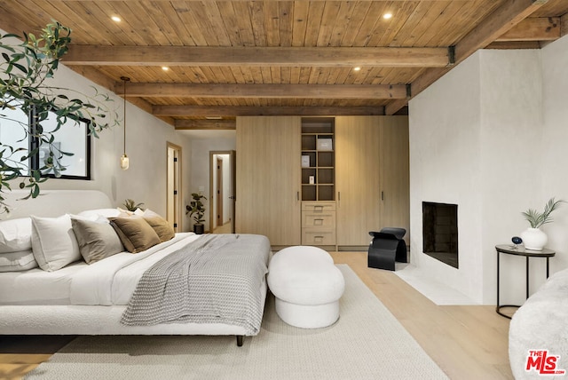 bedroom with a fireplace, wooden ceiling, light hardwood / wood-style floors, and beamed ceiling