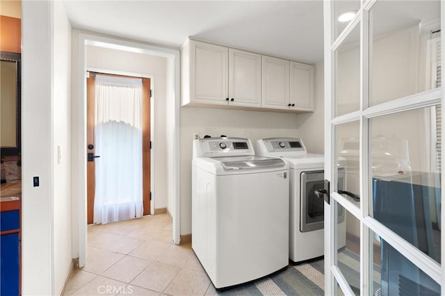 clothes washing area with cabinets, light tile patterned flooring, and washer and clothes dryer