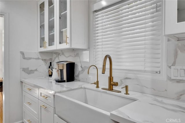 kitchen with light stone countertops, sink, decorative backsplash, and white cabinets