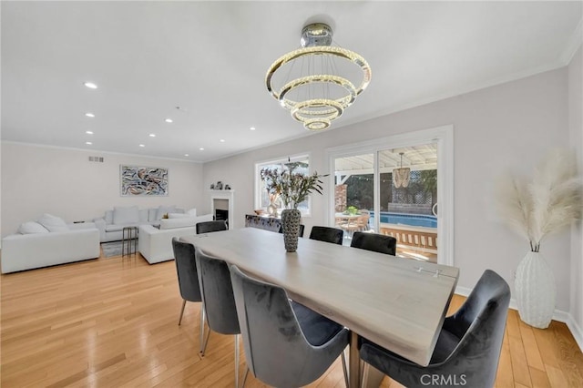 dining area featuring ornamental molding, a chandelier, and light hardwood / wood-style floors