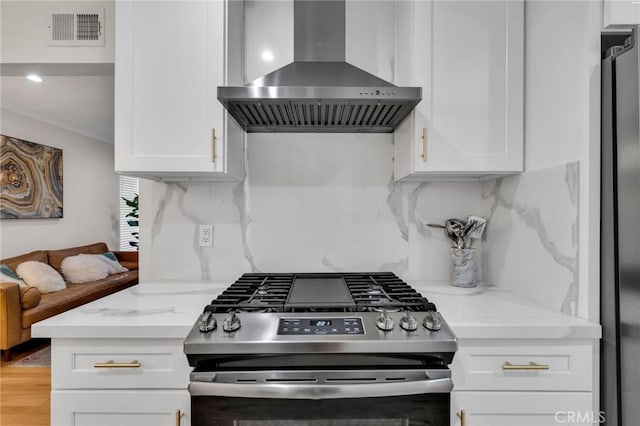 kitchen featuring stainless steel appliances, extractor fan, light stone counters, and white cabinetry