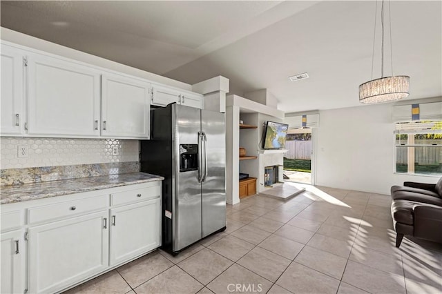 kitchen with light tile patterned floors, white cabinets, open floor plan, stainless steel fridge, and decorative light fixtures