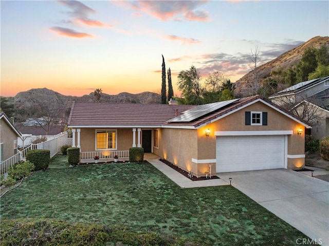 single story home with a porch, stucco siding, a mountain view, and roof mounted solar panels