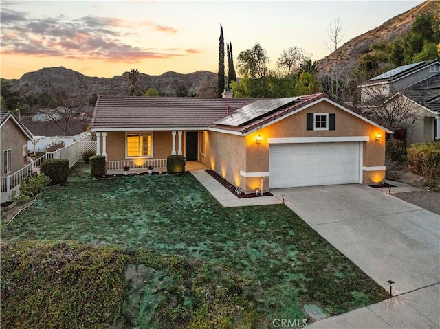 ranch-style home with a mountain view, a garage, solar panels, and covered porch