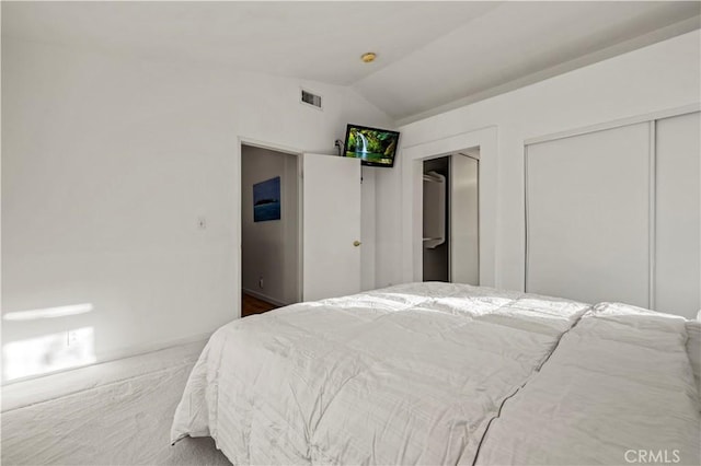 carpeted bedroom featuring visible vents, vaulted ceiling, and two closets