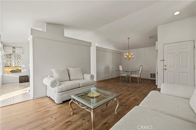 living area with visible vents, lofted ceiling, wood finished floors, a notable chandelier, and recessed lighting