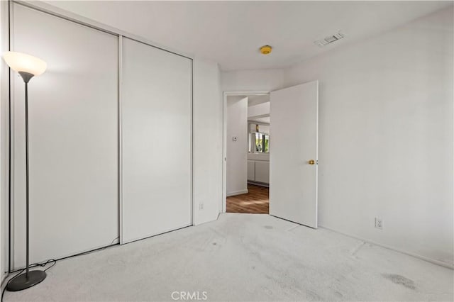 unfurnished bedroom featuring a closet, visible vents, and light carpet