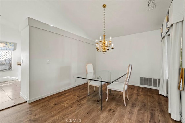 dining area featuring lofted ceiling, hardwood / wood-style flooring, a chandelier, and visible vents