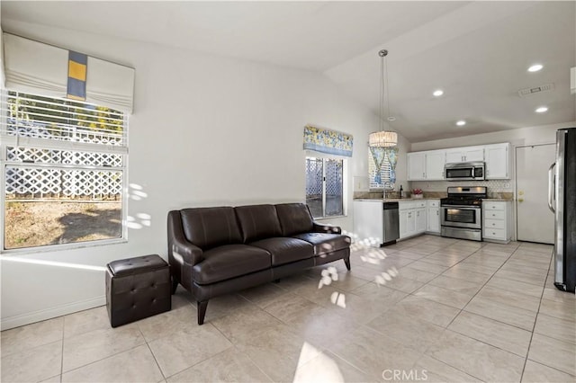 interior space with visible vents, white cabinets, open floor plan, hanging light fixtures, and stainless steel appliances