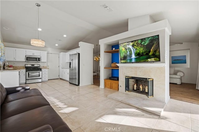 living room with light tile patterned flooring, visible vents, vaulted ceiling, and a high end fireplace