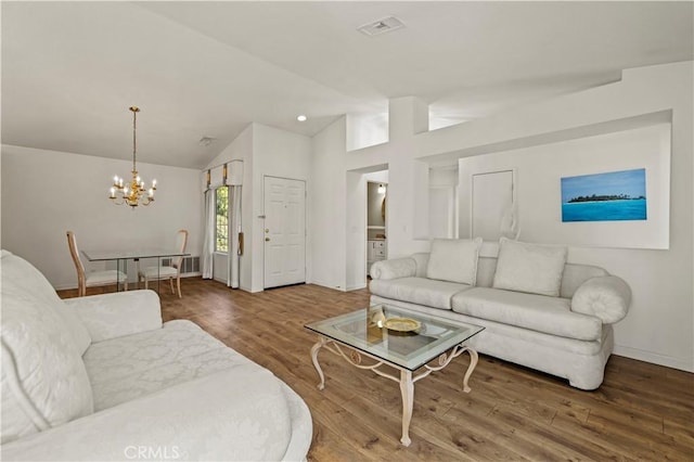 living room with a chandelier, wood finished floors, visible vents, baseboards, and vaulted ceiling