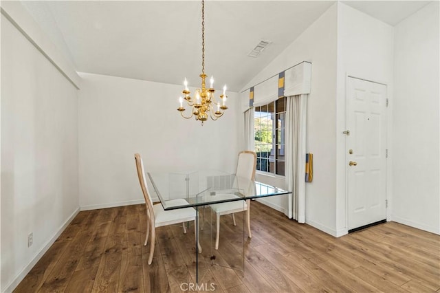 dining area featuring lofted ceiling, wood finished floors, visible vents, baseboards, and an inviting chandelier