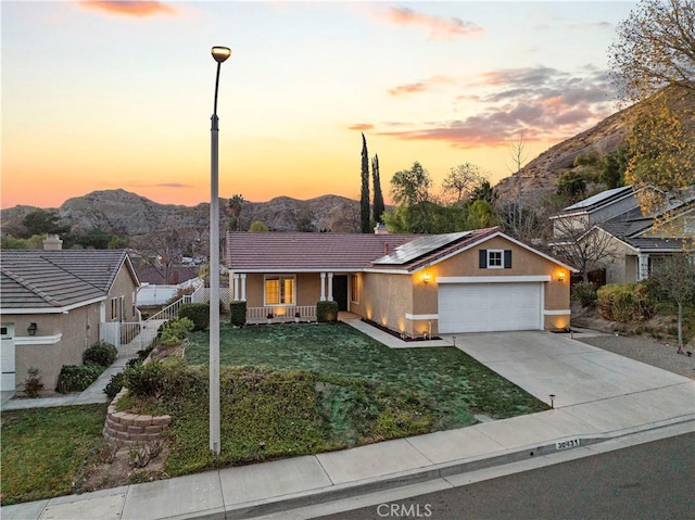 single story home with a mountain view, driveway, a front lawn, and solar panels