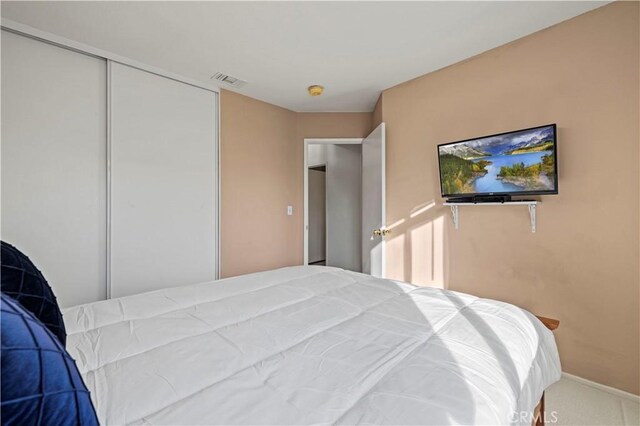 carpeted bedroom featuring a closet, visible vents, and baseboards