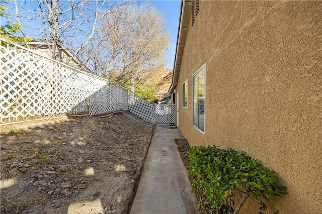 view of side of property featuring a fenced backyard and stucco siding