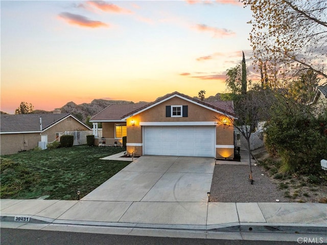 view of front facade with a garage, concrete driveway, a tiled roof, stucco siding, and a front yard