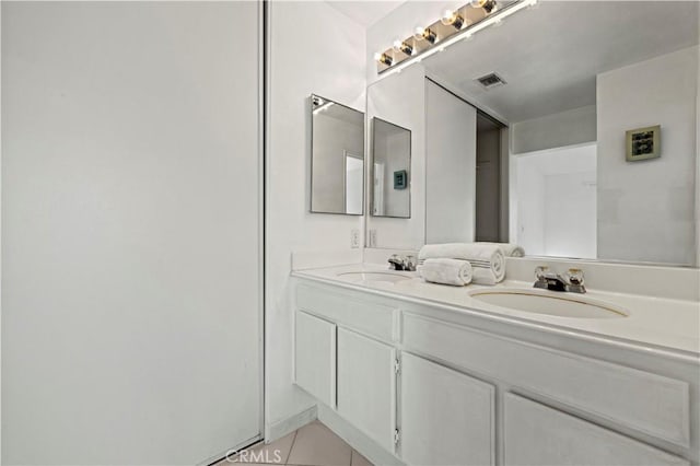 bathroom with double vanity, a sink, visible vents, and tile patterned floors