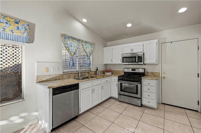 kitchen featuring light tile patterned floors, decorative backsplash, appliances with stainless steel finishes, white cabinets, and a sink