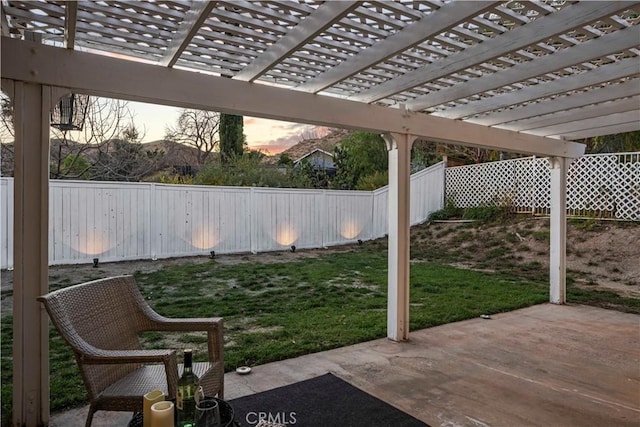 patio terrace at dusk featuring a fenced backyard, a lawn, and a pergola