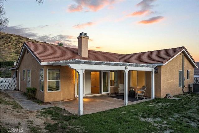 30431 Sunrose Pl, Canyon Country, CA 91387 - back of property at dusk featuring a chimney, stucco siding, a patio, and a tile roof