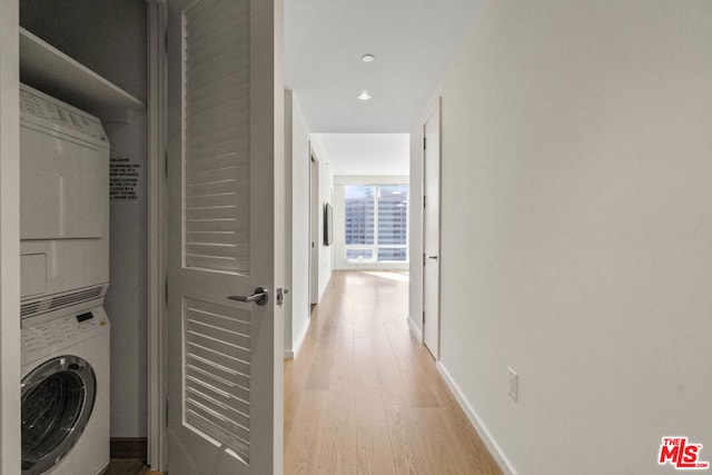 laundry room featuring light hardwood / wood-style floors and stacked washer and clothes dryer