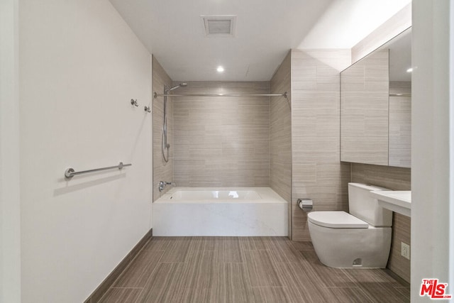 full bathroom with shower / bathing tub combination, vanity, toilet, and tile walls