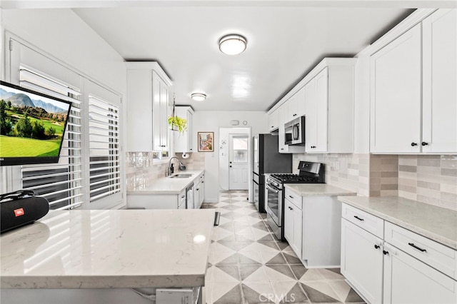 kitchen with white cabinetry, sink, backsplash, light stone counters, and stainless steel appliances