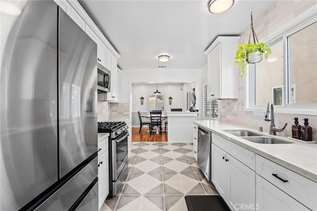 kitchen featuring white cabinetry, appliances with stainless steel finishes, sink, and decorative light fixtures