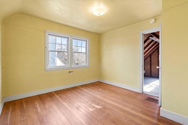 unfurnished room featuring hardwood / wood-style flooring and lofted ceiling