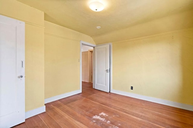 unfurnished room featuring wood-type flooring and vaulted ceiling