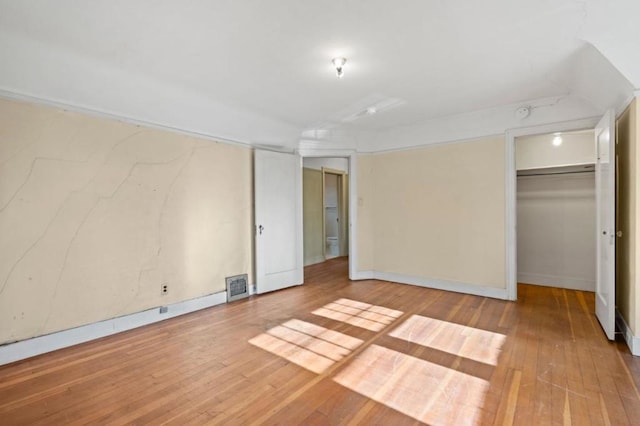 unfurnished bedroom with a spacious closet, a closet, and light wood-type flooring