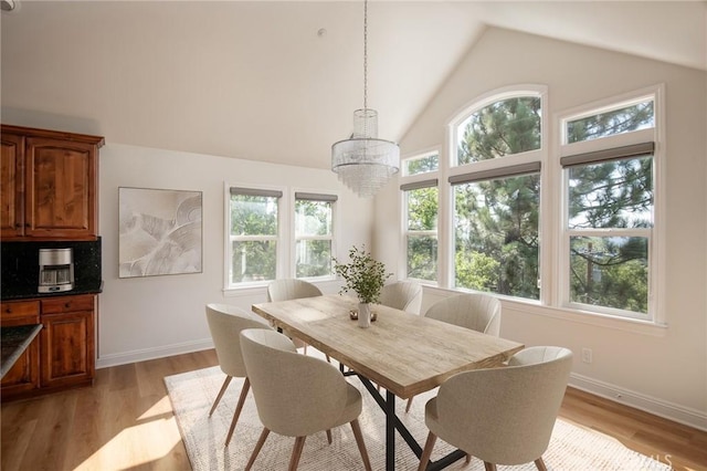 dining area featuring an inviting chandelier, light hardwood / wood-style flooring, and vaulted ceiling