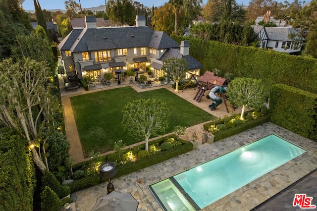 rear view of house featuring a lawn, a balcony, a playground, and a patio area