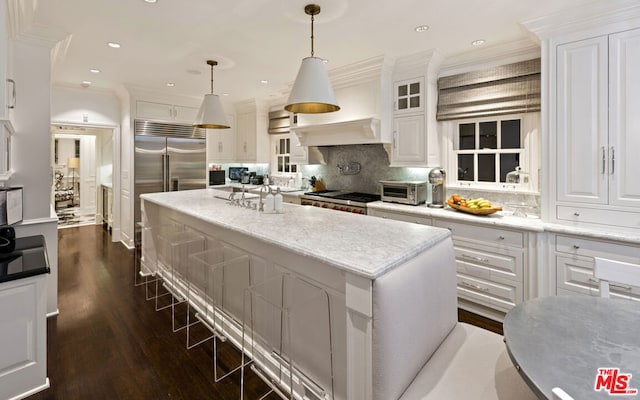 kitchen with dark hardwood / wood-style floors, decorative light fixtures, white cabinetry, a center island, and crown molding