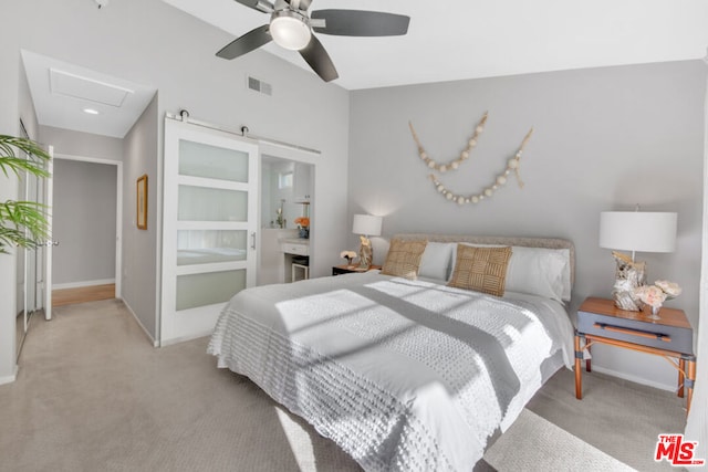 bedroom with ensuite bath, light colored carpet, and ceiling fan